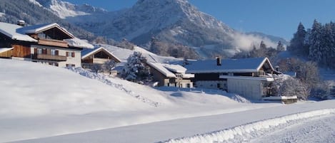 Paisaje nevado de montañas con una hilera de chalés de madera.