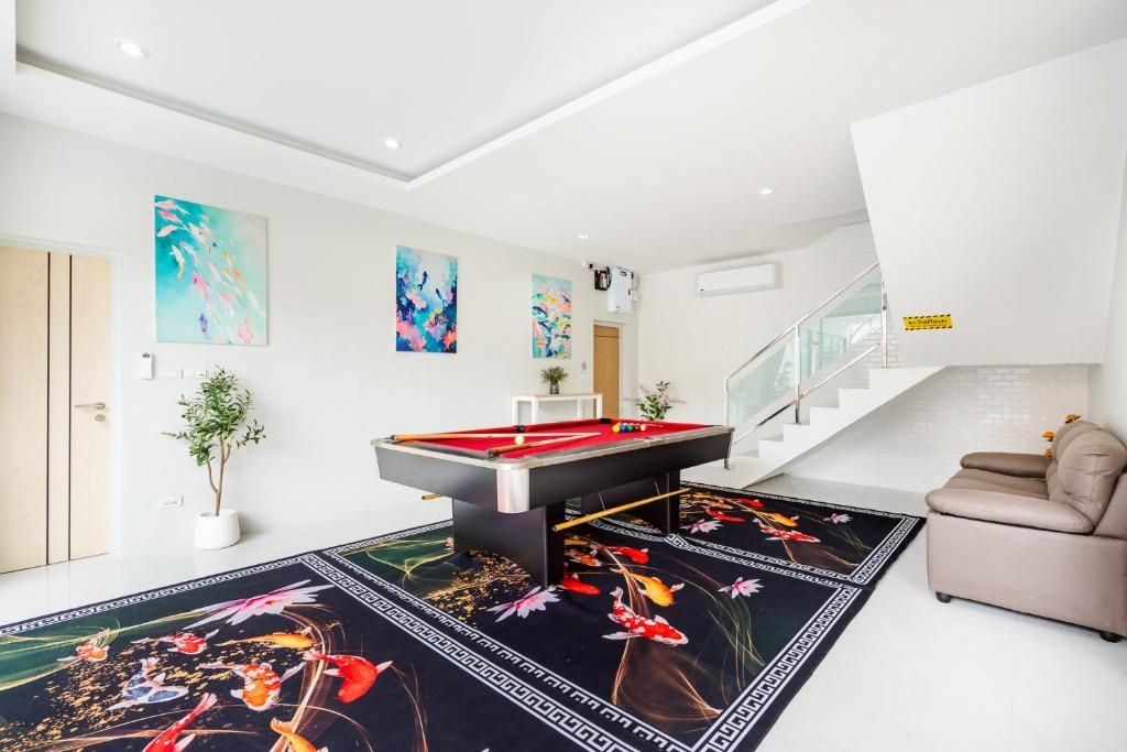 A modern living room with a pool table, a sofa, and a staircase.