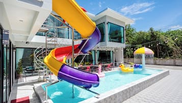 Un edificio moderno con área de piscina, tobogán de varios colores y un pato flotador.
