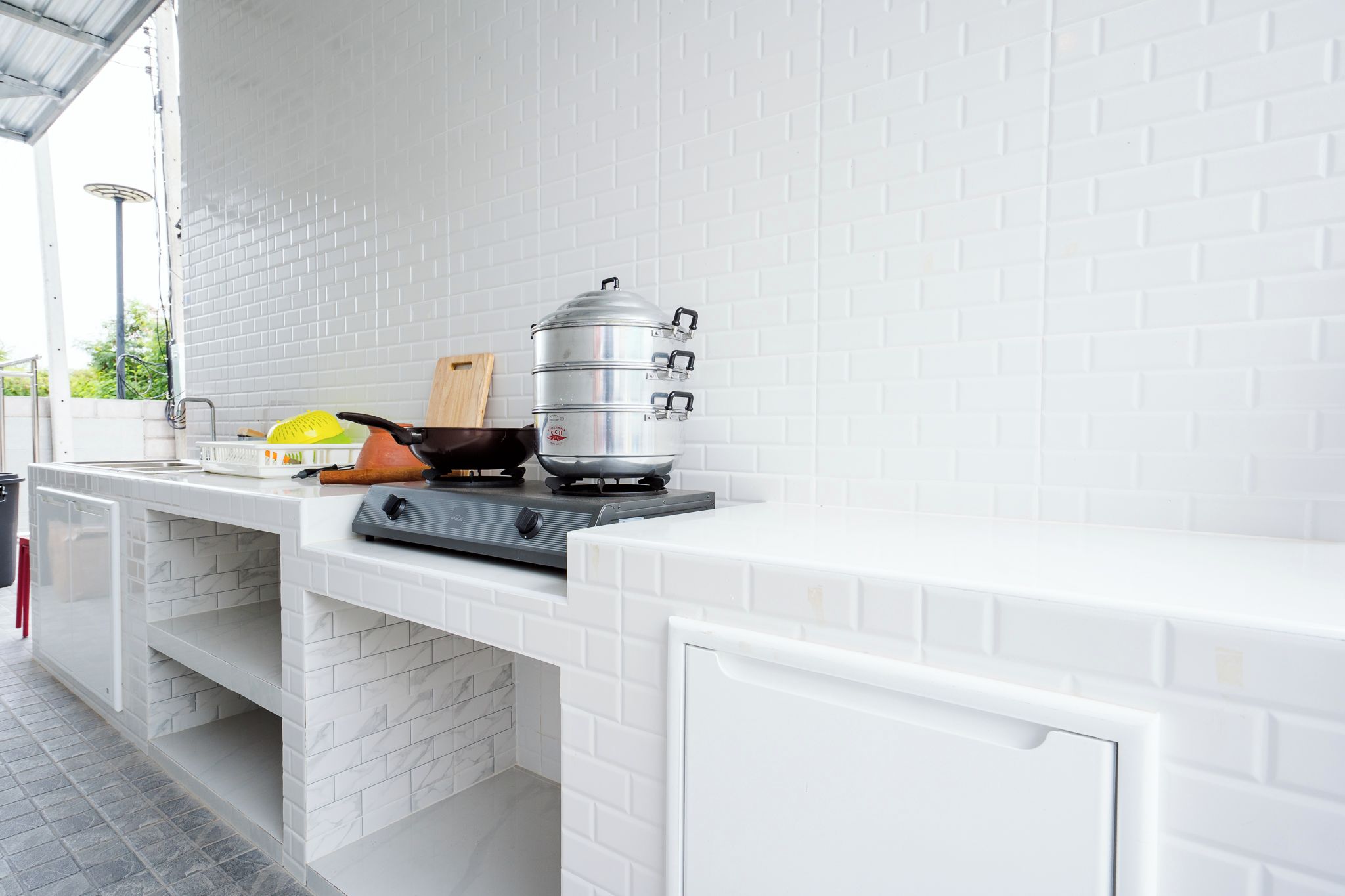 A kitchen with a built-in stove, a large pot, and a colander on the counter.