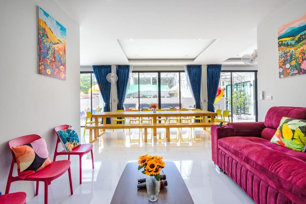 A modern living room with a red sofa, a coffee table with a vase of flowers, and a dining area with a yellow table and chairs.