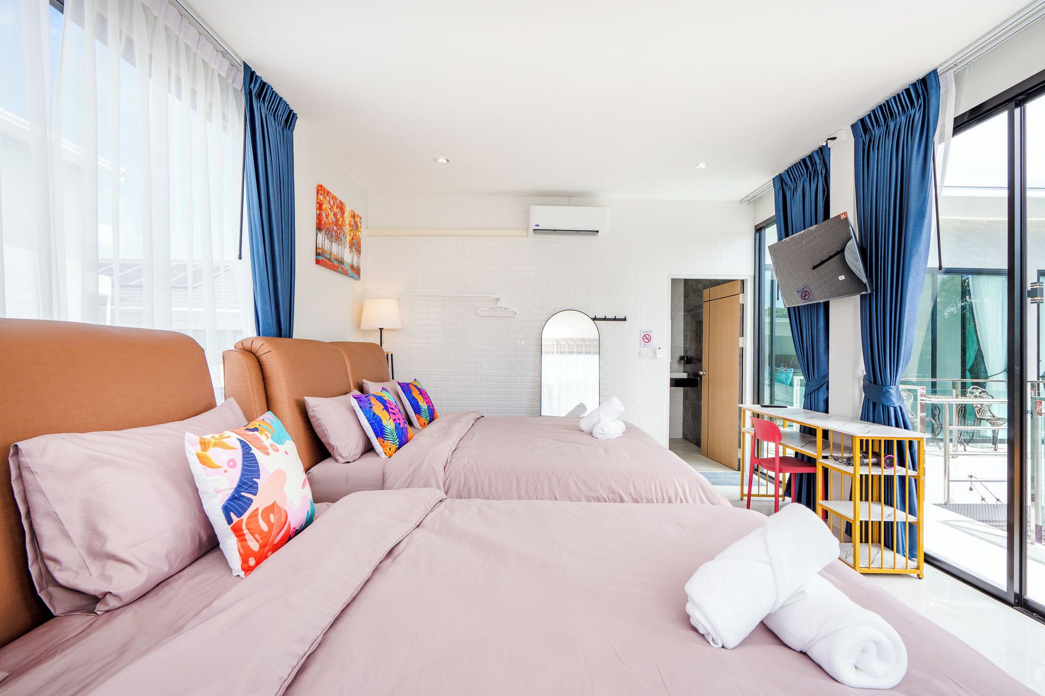 Quarto de hotel com uma cama grande, escrivaninha, televisão e varanda com vista.