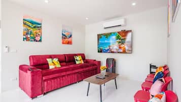 Una sala de estar con un sofá rojo, una mesa de centro y obras de arte en las paredes.