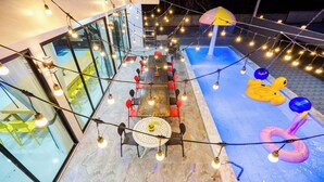 An outdoor dining area with string lights, tables, chairs, and a pool with inflatable toys. - Love U Pool Villa-Hua Hin (Tambon Hua Hin)