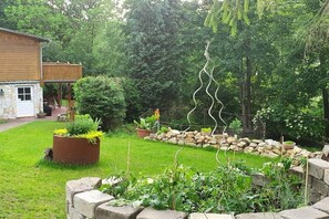 Een tuin met een houten terras, stenen muren en verschillende planten.