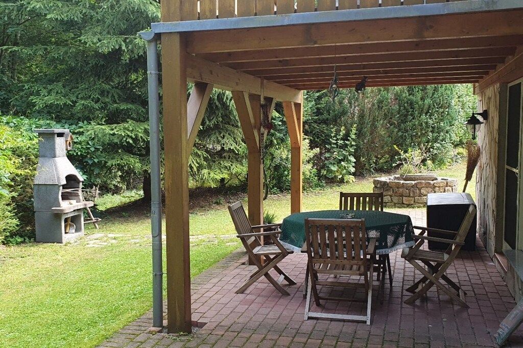 Eine Terrasse im Freien mit Pflasterboden, Holzmöbeln und einem Kamin aus Stein.