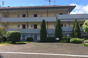 A multi-story building with a flat roof, several balconies, and a parking area in front. - Mati's panoramic view (Meersburg)