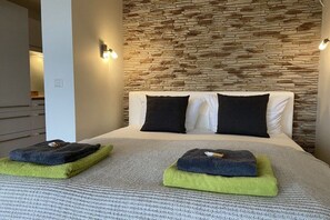 A bed with a stone wall backdrop, two pillows, and folded towels. - Mati's panoramic view (Meersburg)