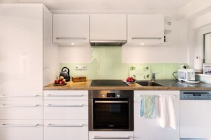 A modern kitchen with white cabinetry, a Bosch oven, a coffee maker, and a dishwasher. - Mati's panoramic view (Meersburg)