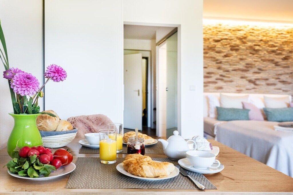 A breakfast setup with croissants, juice, and a vase of flowers.