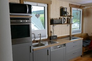 A compact kitchen with a microwave, oven, and sink. - Holiday home with 2 bedrooms (Lennestadt-Milchenbach)