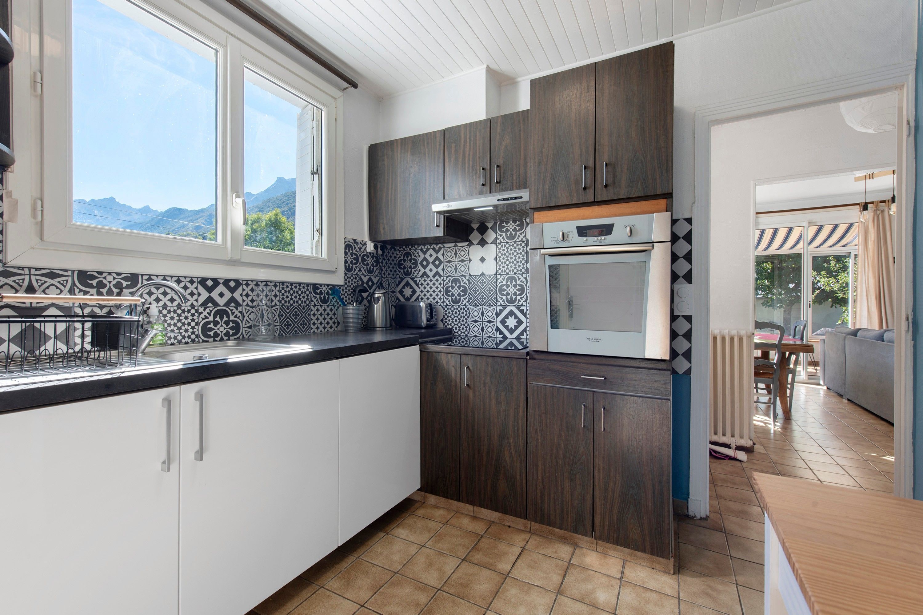 Una cucina moderna con un'ampia finestra, uno schienale decorativo e mobili in legno.