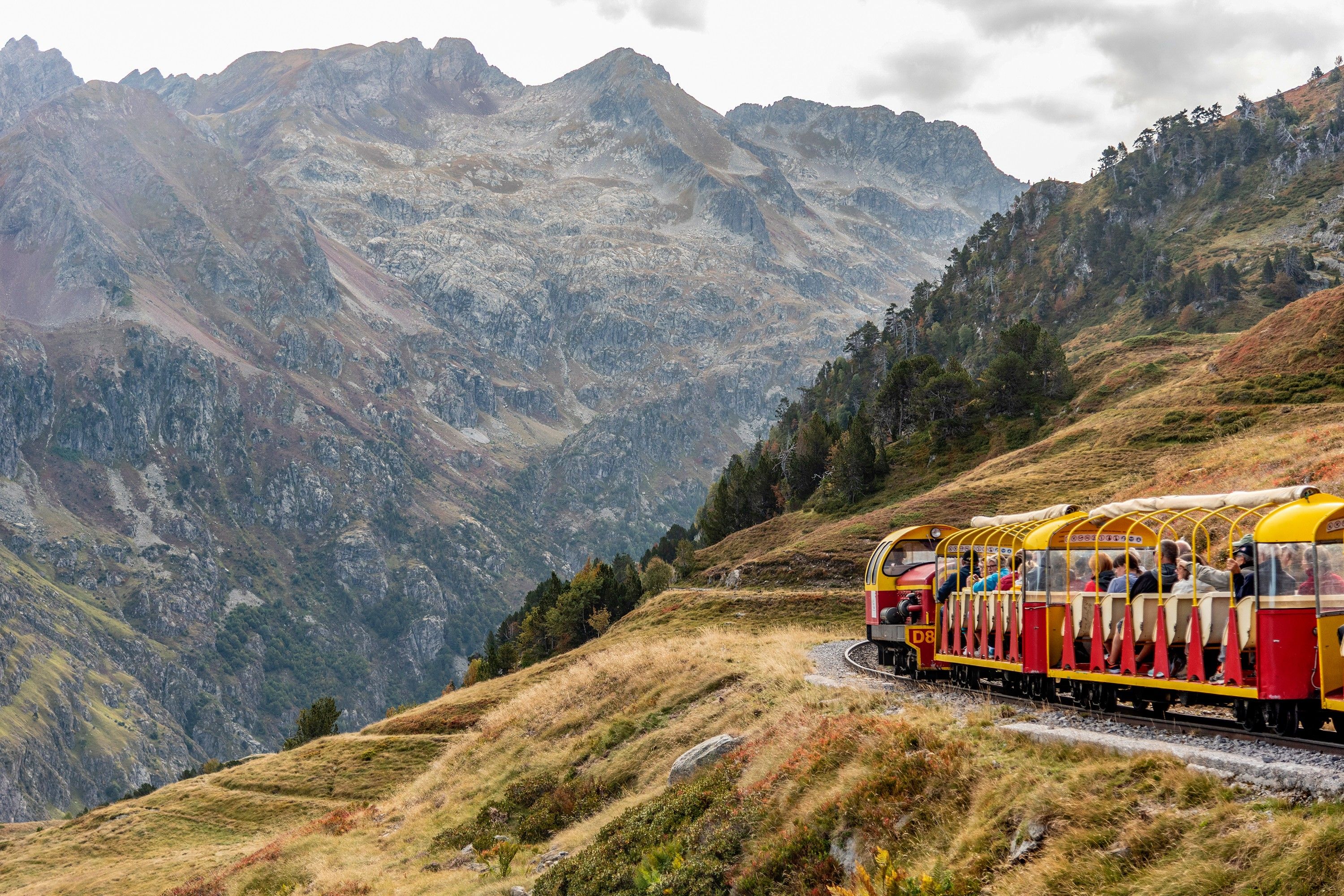 Un tren con pasajeros viajando a través de un paisaje montañoso.