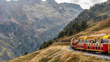 Un tren con pasajeros viajando a través de un paisaje montañoso.