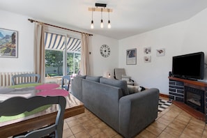 A living room with a sofa, television, fireplace, and artwork on the wall. - Holiday Home 'Chez Négus' with Wi-Fi and Air Conditioning (Laruns)