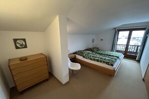 A bedroom with a bed, a dresser, a chair, and a window. - Holiday apartment with 1 bedroom (Reit im Winkl)
