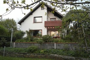 A two-story house with a sloped roof, a balcony on the upper floor, and a stone retaining wall in front. - in the romantic Rhine Valley near Bonn (Rheinbreitbach)