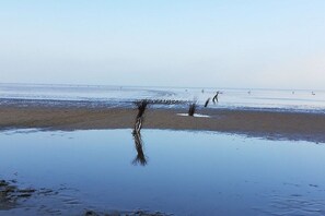 A beach with calm water, a few people, and some vegetation. - Holiday apartment with 1 bedroom (Cuxhaven)
