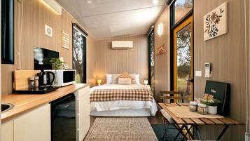 Una habitación pequeña con cama, mesita de noche y una kitchenette.