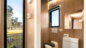 A bathroom with a toilet, sink, and window.
