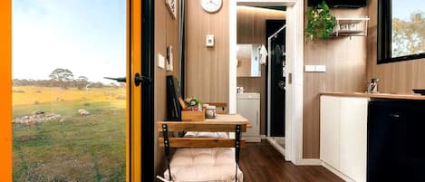 A compact kitchen with a wooden countertop, a sink, and a window overlooking a grassy area.