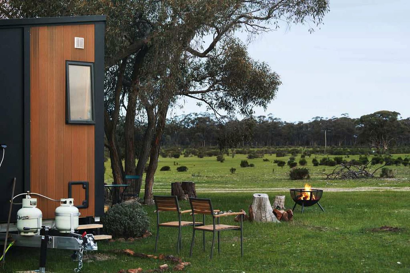A modern outdoor area with a wooden structure, outdoor seating, and a fire pit.