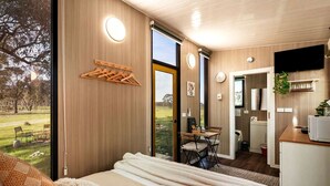 A bedroom with a bed, a desk, and a view of a garden.