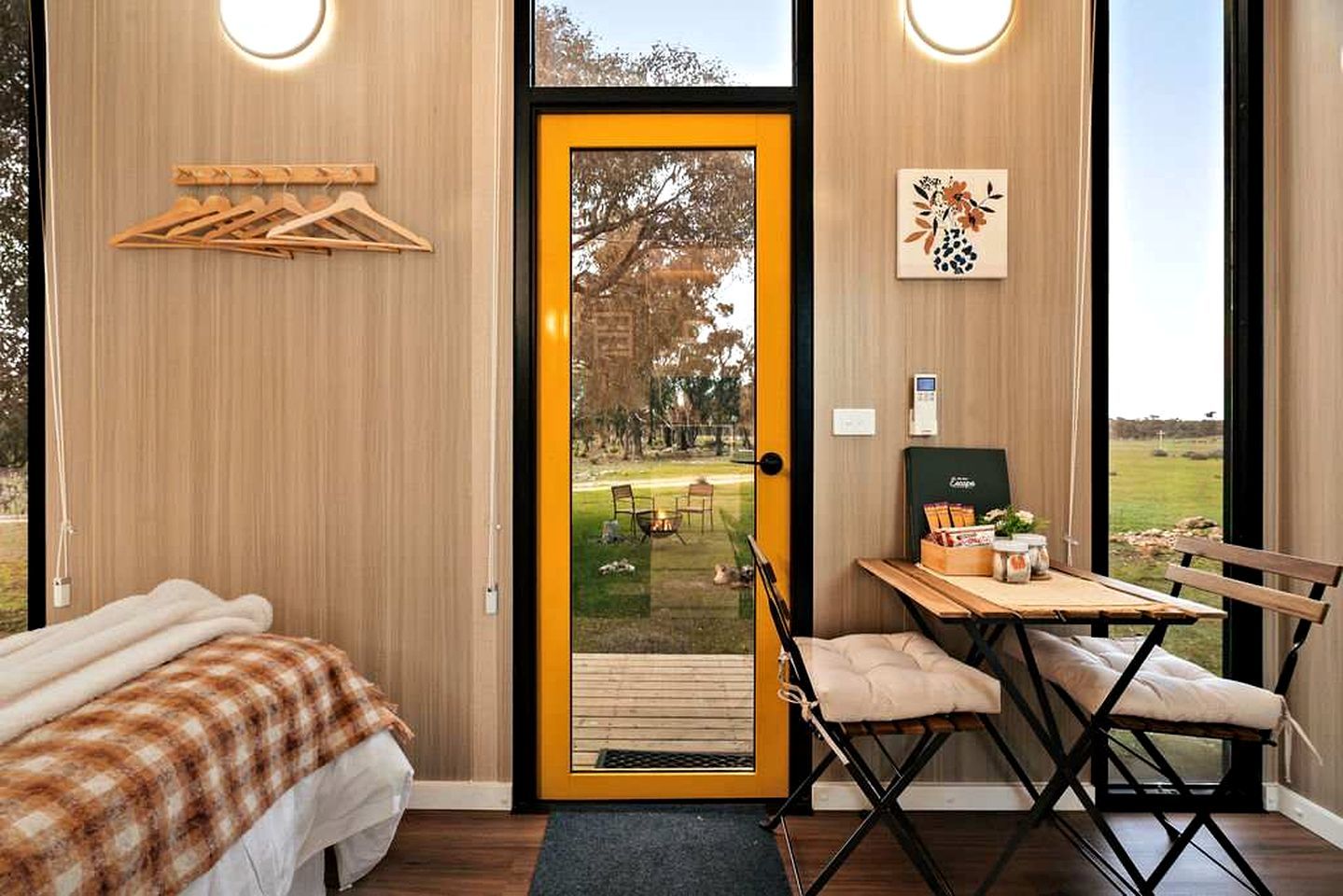 A room with a bed, a chair, a table, and a door leading to an outdoor area.