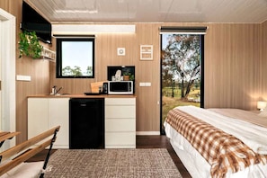 Une chambre moderne avec un lit, une petite kitchenette et une vue sur l’extérieur.