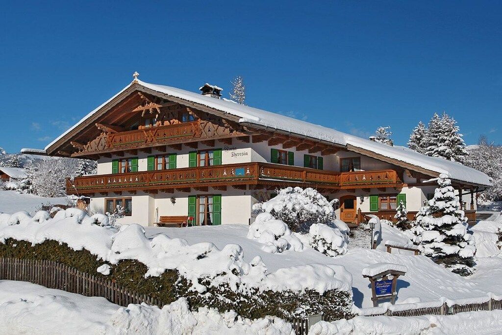 Un chalet traditionnel avec un toit en pente, des balcons en bois et une enseigne indiquant « Sherpaen ».