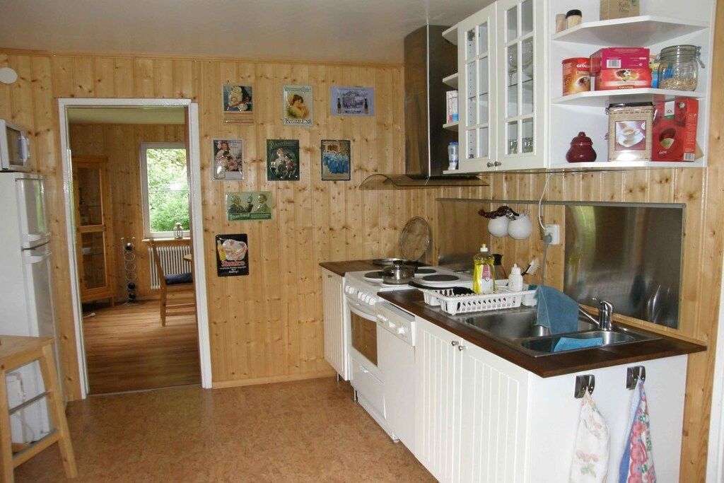 A kitchen with wooden walls, white cabinets, a stove, and a sink.