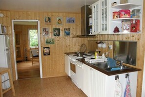 A kitchen with wooden walls, white cabinets, a stove, and a sink. - Holiday home in Bullaren with swimming pool (Bullaren)