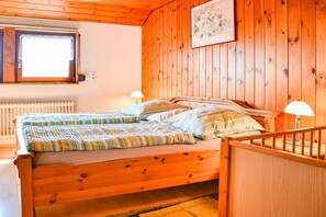 A wooden bed with a quilt, two bedside lamps, and a window with blinds. - at the Storzenhof || Tennenbronn (Tennenbronn)