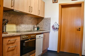 Una cocina con armarios de madera, estufa, horno, lavavajillas y fregadero.
