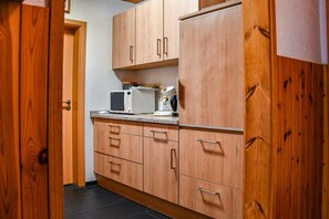 Eine Küche mit Holzschränken, einer Mikrowelle und einem Wasserkocher auf der Arbeitsfläche.