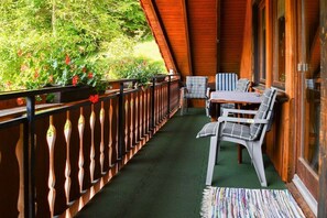 A wooden deck with a table and chairs, surrounded by a railing and greenery. - at the Storzenhof || Tennenbronn (Tennenbronn)