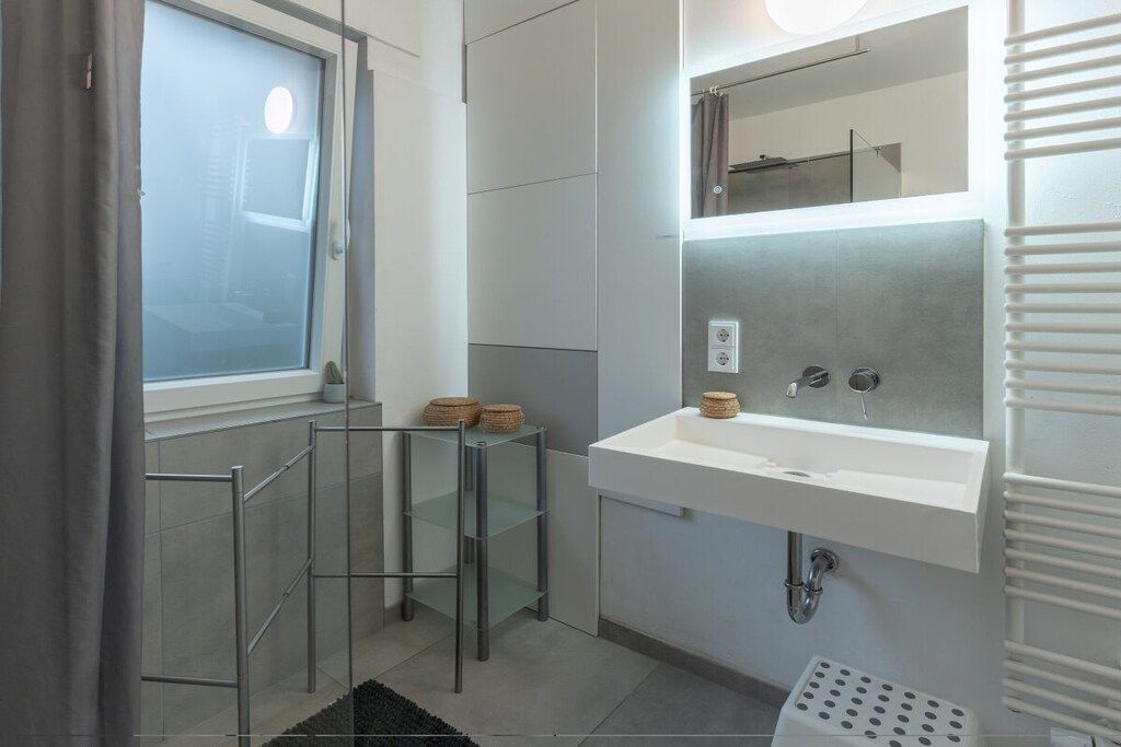 A modern bathroom with a glass partition, a white sink, and a towel rack.