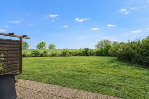 A grassy outdoor area with a wooden fence and a bench. - Holiday apartment Deichblick (Dangast)
