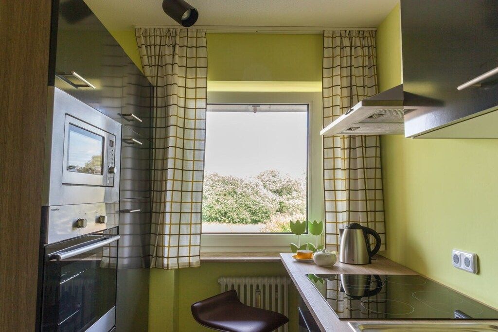 A compact kitchen with a window, a built-in oven, a stove, and a small dining area.