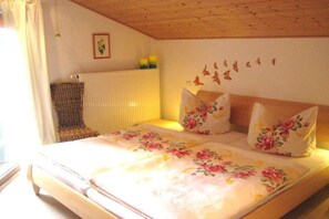 A bedroom with a bed, floral bedding, a radiator, a chair, and wall decorations. - 3 on the Demelhof || Bernau (Bernau)