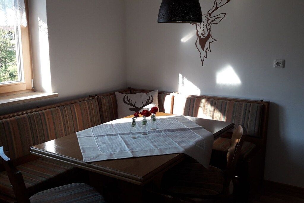 Een eethoek met een tafel voor twee personen, een bank en een op de muur bevestigde decoratie van een hertenkop.