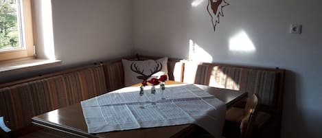 Een eethoek met een tafel voor twee personen, een bank en een op de muur bevestigde decoratie van een hertenkop.
