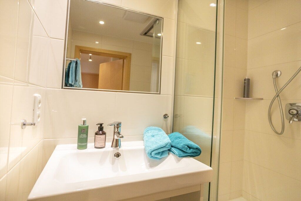 A bathroom with a white sink, a mirror, and a glass-enclosed shower area.