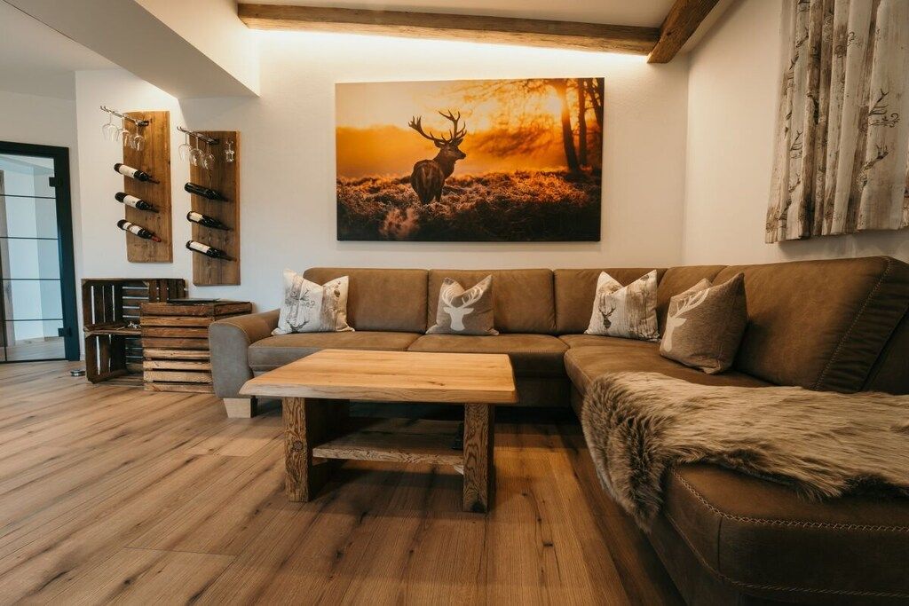 Un salon moderne avec un canapé d’angle, une table basse en bois et un porte-bouteilles fixé au mur.