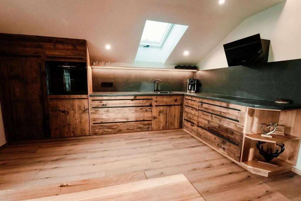 Une cuisine avec des meubles en bois, un puits de lumière et un four encastré.