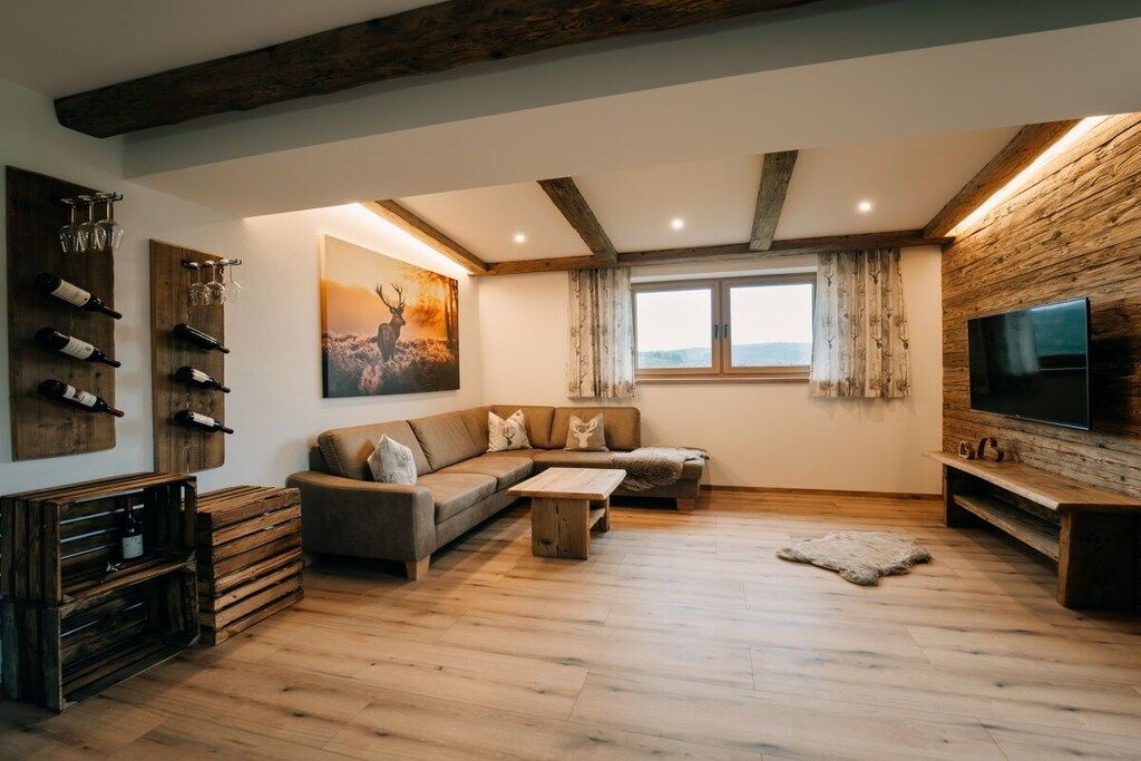 Ein Wohnzimmer mit Holzboden, einer Couch, einem Couchtisch, einem Fernseher und einem Weinkühlschrank.