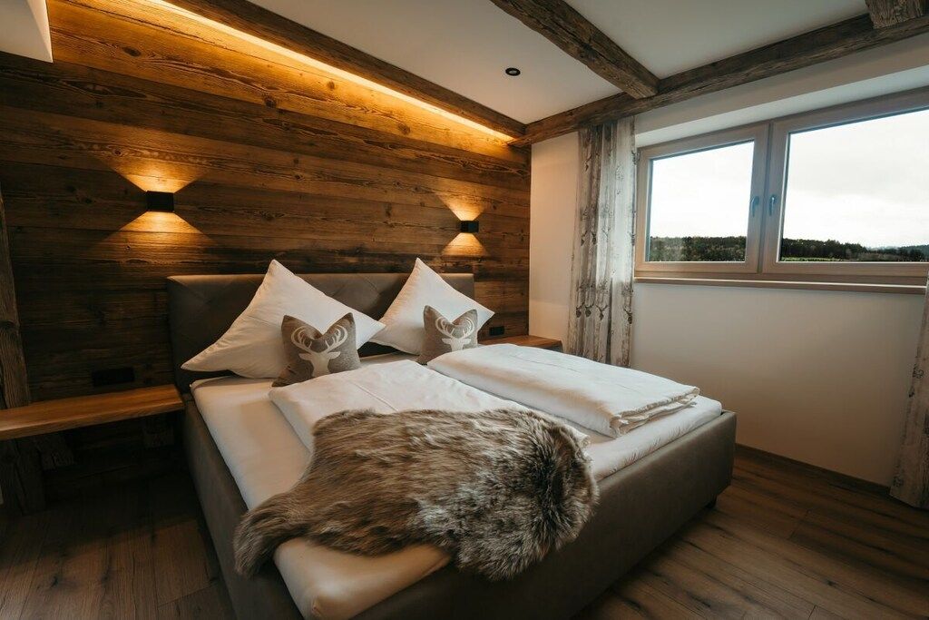 Un dormitorio con cabecera de madera, un ventanal grande y un cubrecama de piel.