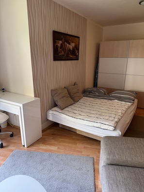 Ein Schlafzimmer mit Bett, Schreibtisch und Kleiderschrank.
