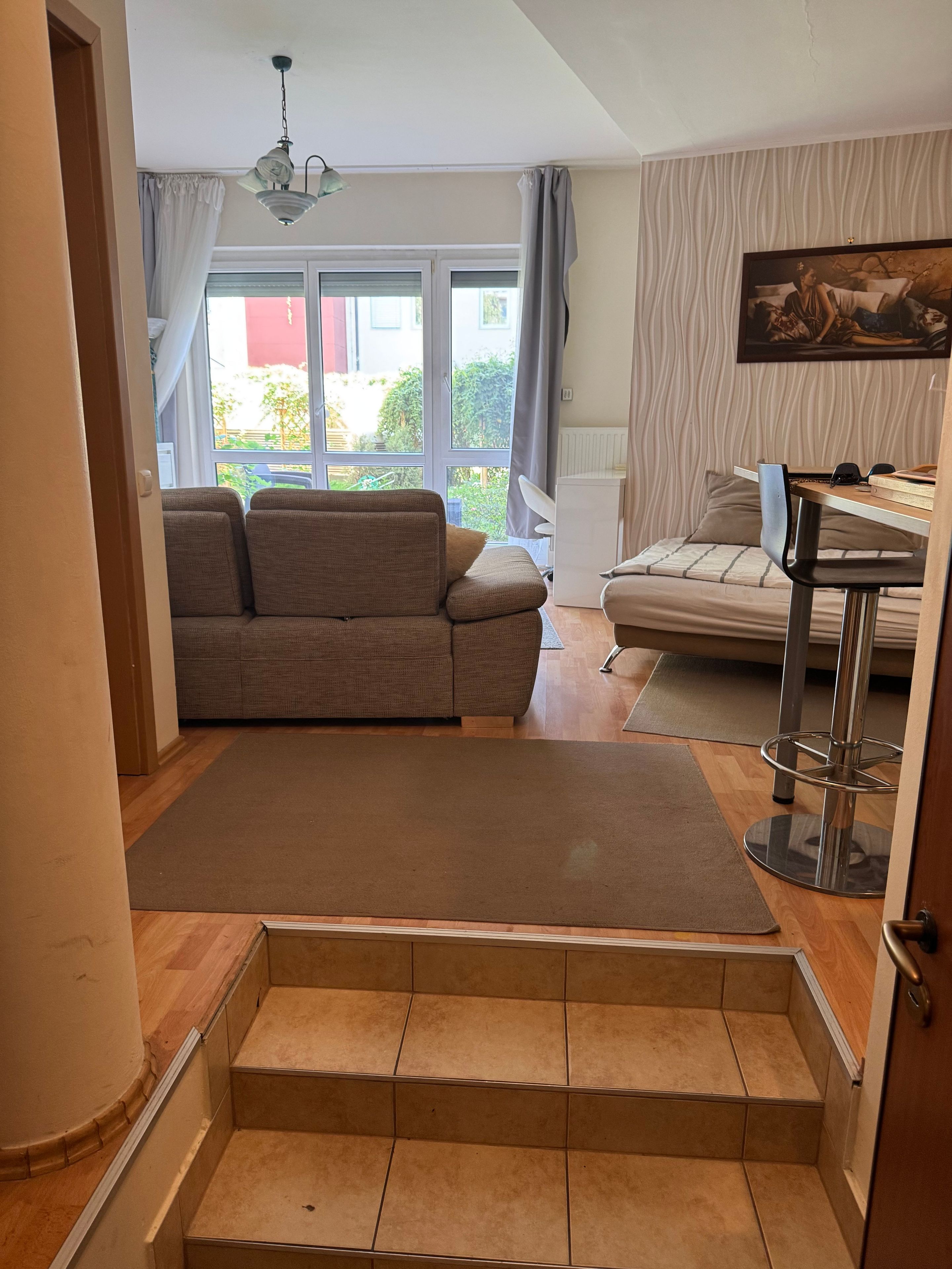 Ein Wohnzimmer mit einer Couch, einem Esstisch und einer Treppe zu einer anderen Ebene.