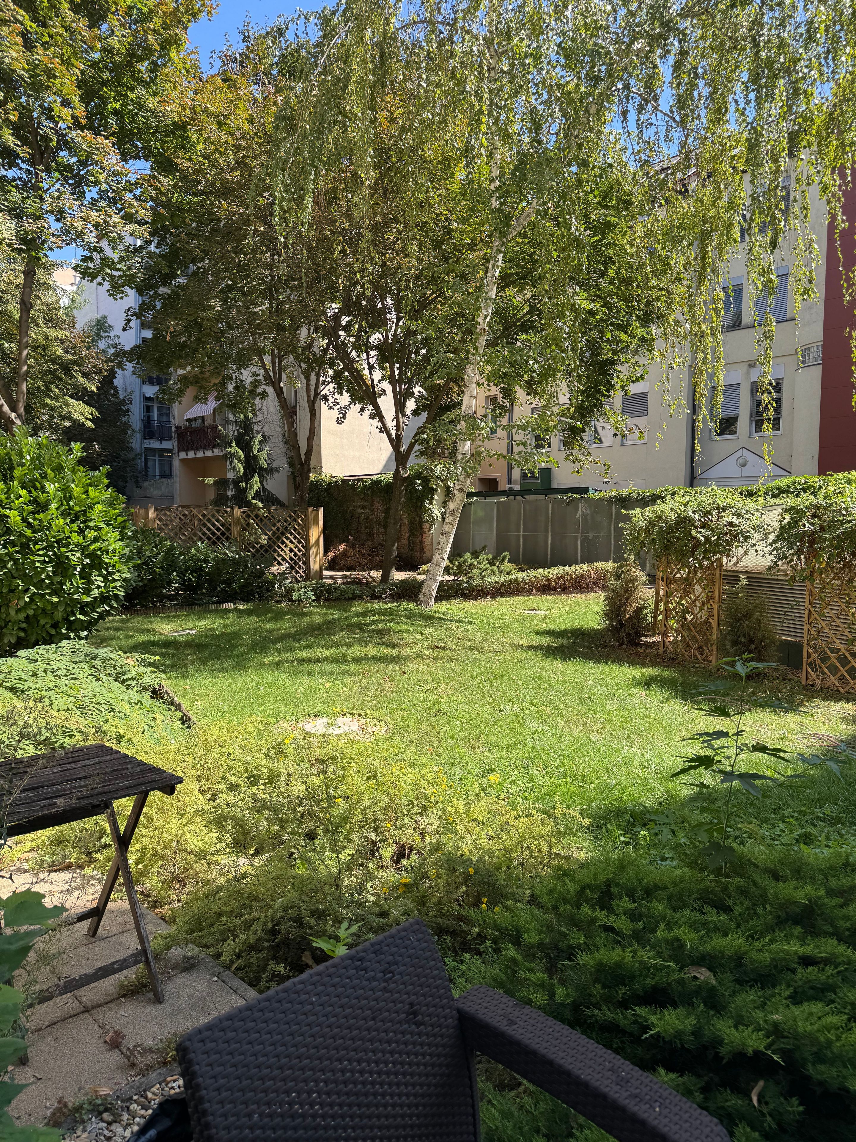 Ein Innenhof mit Rasenfläche, einem Holztisch und einem Stuhl.
